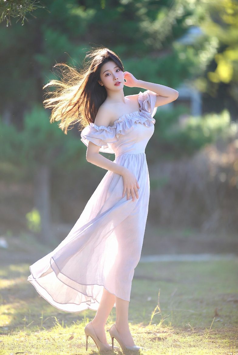 Korean woman in an off-shoulder ruffle dress posing in soft warm light.