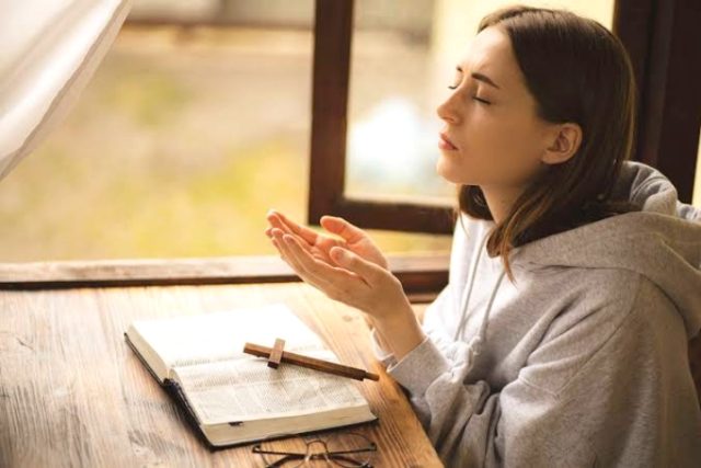Single mom praying over budget with Bible, avoiding debt with faith and wisdom